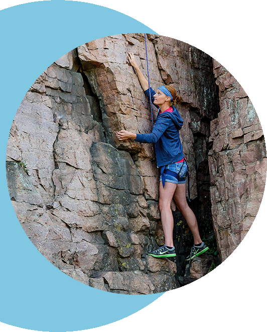 A woman rock climbing a sheer vertical cliff.