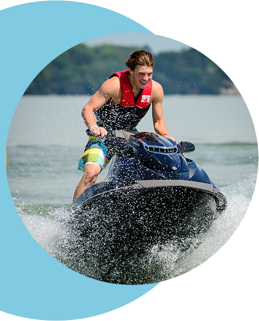 A man with a large smile riding a jet ski.