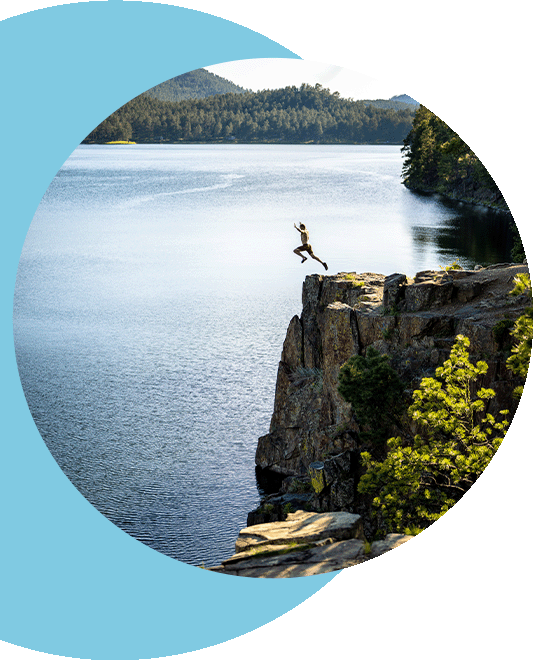 A person jumping off a cliff into a beautiful lake.