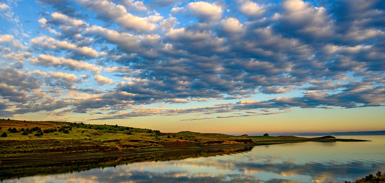 A beautiful landscape shot of the sun setting over a water.