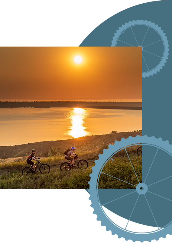 Kids mountain-biking near a lake at sunset.