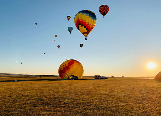 Hot air balloons; one landing on a field.