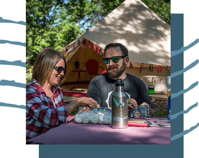A couple making s'mores at a luxury glamping site