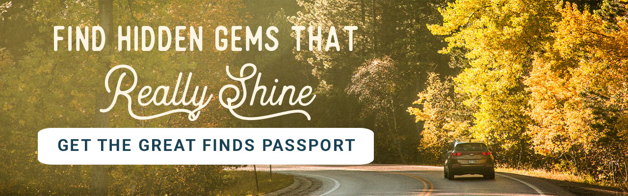 A car drives down a road surrounded by fall-colored trees. A headline reads: Find Hidden Gems That Really Shine. Get The Great Finds Passport.