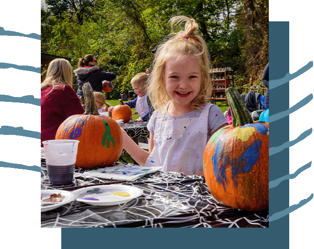 A little girl painting pumpkins.