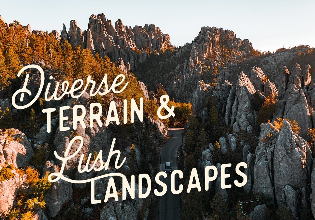 An aerial view of a car traveling through towering rock formations. A headline reads: Diverse Terrain & Lush Landscapes
