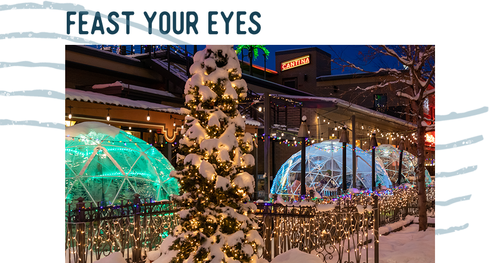 A snowy street decorated like a Christmas village. A headline reads: Feast Your Eyes.