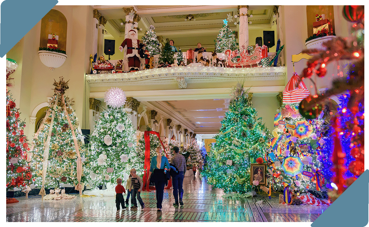 A family walking through the Capitol surrounded by lit christmas trees.