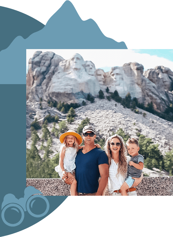 A family posing for a photo, with Mount Rushmore behind them in the distance.