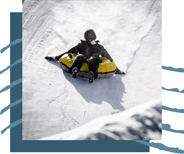 A person riding a tube down a snow-covered hill.
