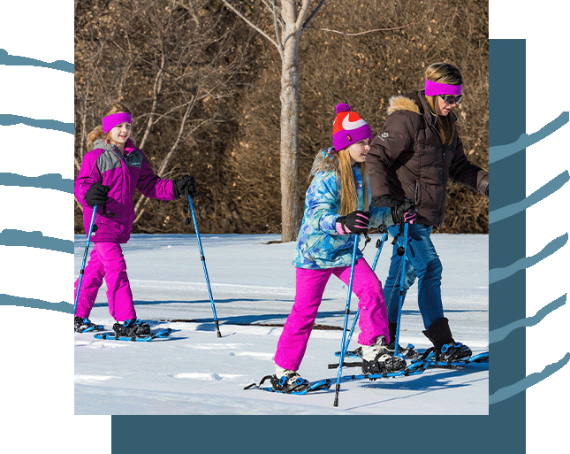 A family with snowshoes out hiking in the snow.