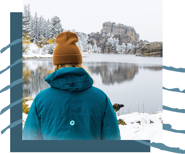 A person overlooking a beautifully reflective lake in the winter time.