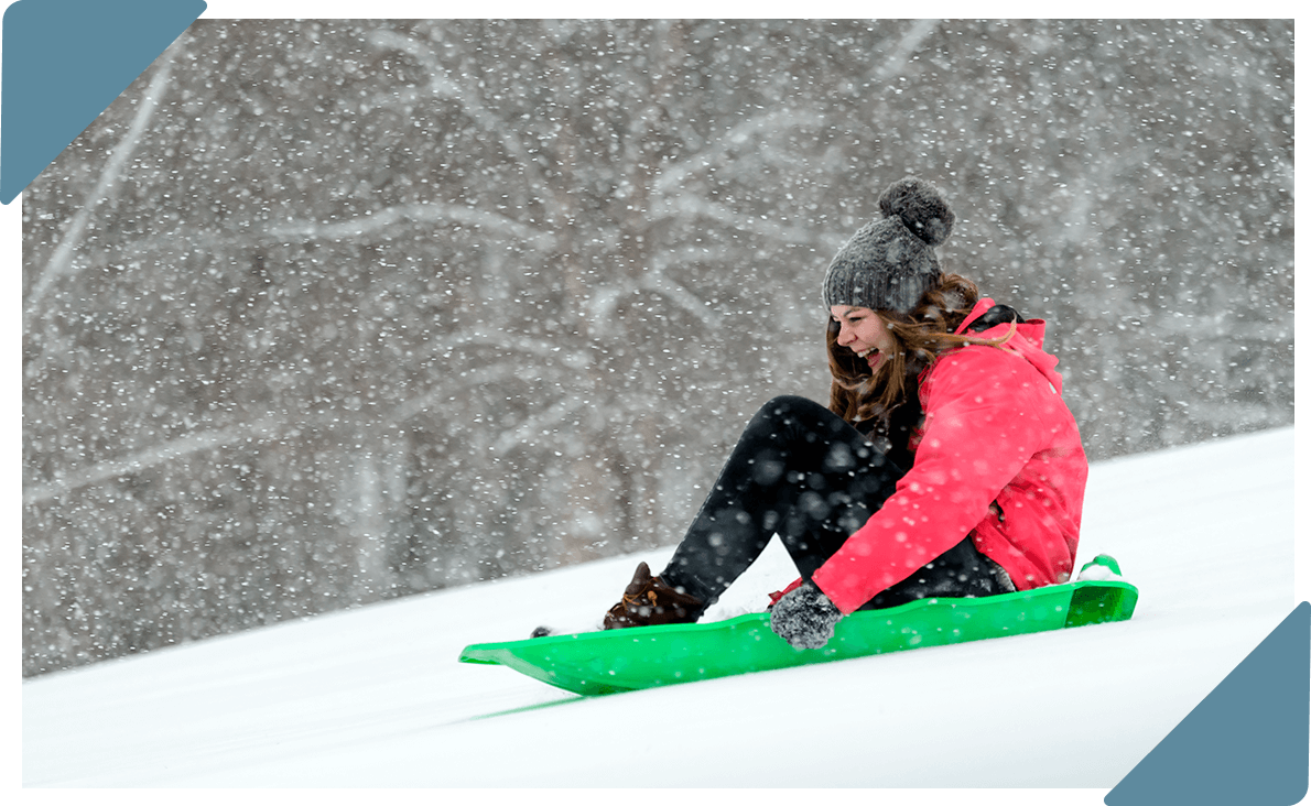 A girl sledding down a hill in the snow.