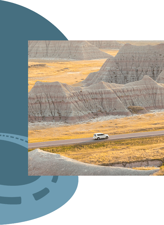 Image of car driving on road along rock formations.